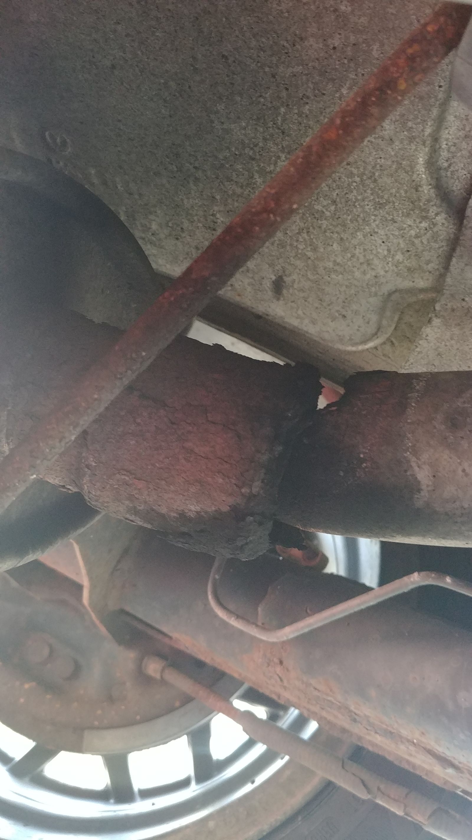 Right behind the muffler. Completely rusted through.