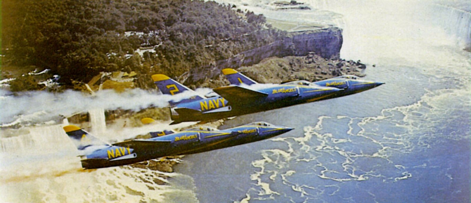 U.S. Navy Grumman F11F-1 Tiger fighters from the “Blue Angels” aerobatics team, flying over the Niagara Falls, New York (USA). The “Blue Angels” originally flew the F11F “short nose” version.