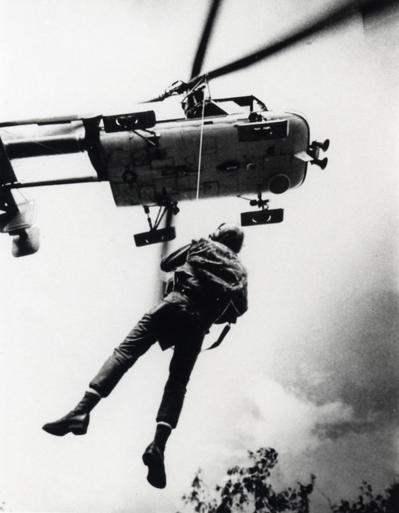 A U.S. Air Force parajumper hanging below a Kaman HH-43B/F Huskie in South-East Asia, in the 1960s.