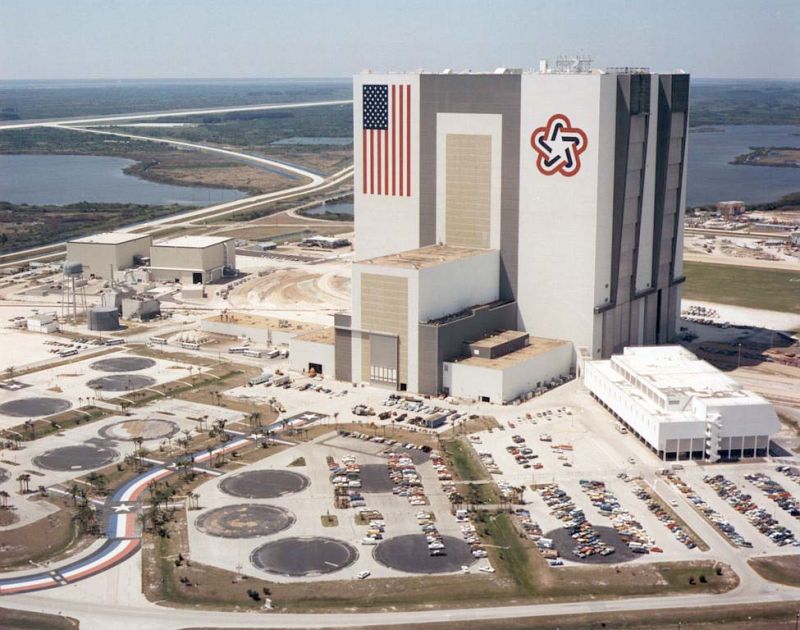 Aerial view of Kennedy Space Center’s Vehicle Assembly Building, with vertical U.S. flag and the emblem of the 1976 bicentennial celebrations which remained in place until 1998