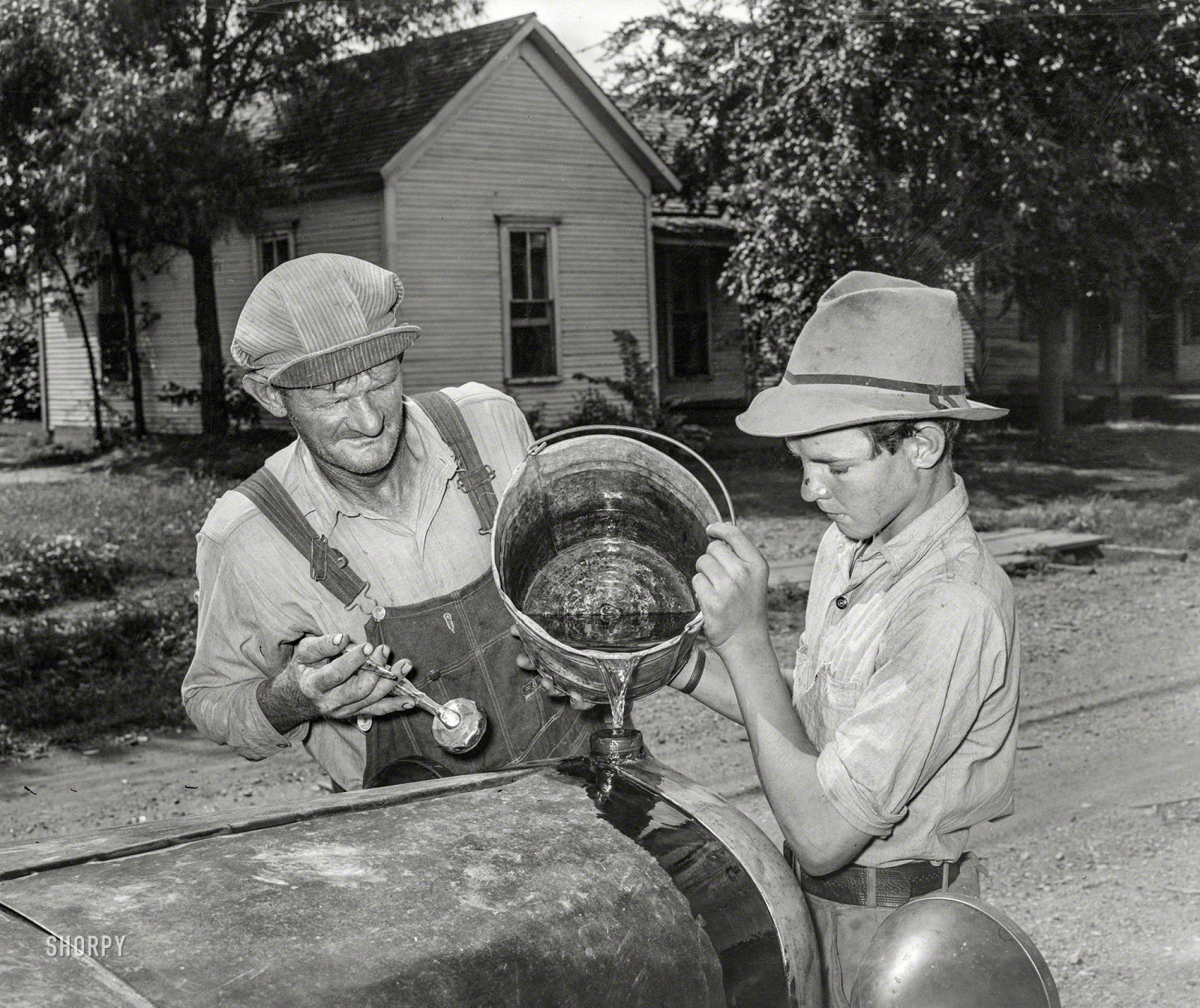 Elmer Thomas and his son top off the radiator before setting out. (Shorpy)