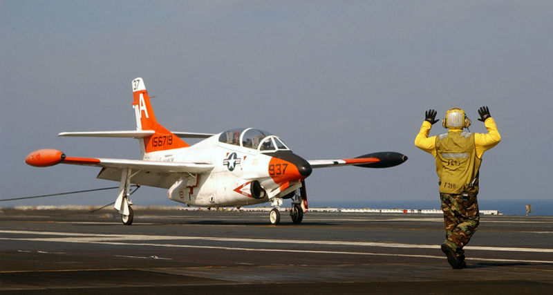 A crewman gives hand signals to a T-2C Buckeye assigned to Training Squadron Nine (VT-9) “Tigers” after catching the arresting gear wire on the flight deck aboard USS Harry S. Truman (CVN 75) in 2003 (US Navy)