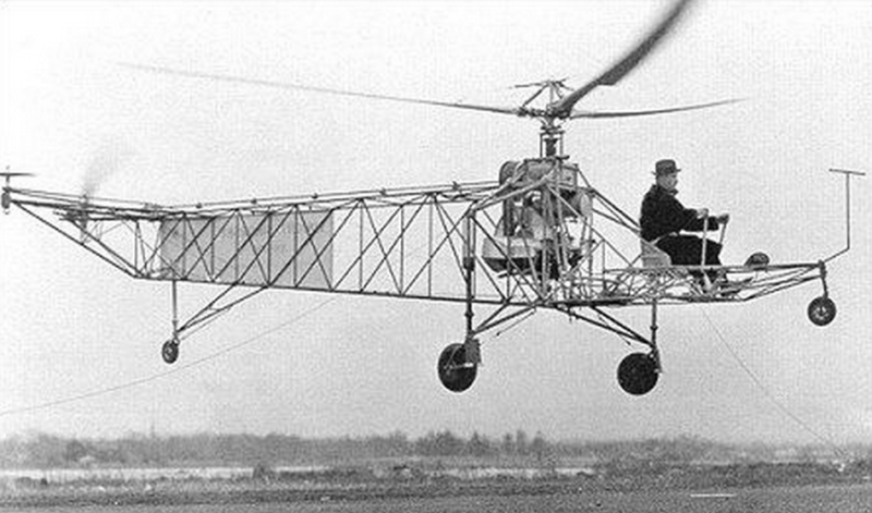 With his trademark fedora, Igor Sikorsky conducts a tethered flight of an early version of the VS-300, with a single anti-torque tail rotor supplemented by twin horizontal tail rotors. (Sikorsky)