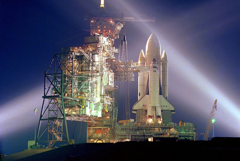 Columbia, with its white external fuel tank and solid rocket boosters, rests on the pad prior to launch. Beginning with STS-3, the Shuttle flew with an unpainted external fuel tank to save roughly 600 pounds of weight. (NASA)