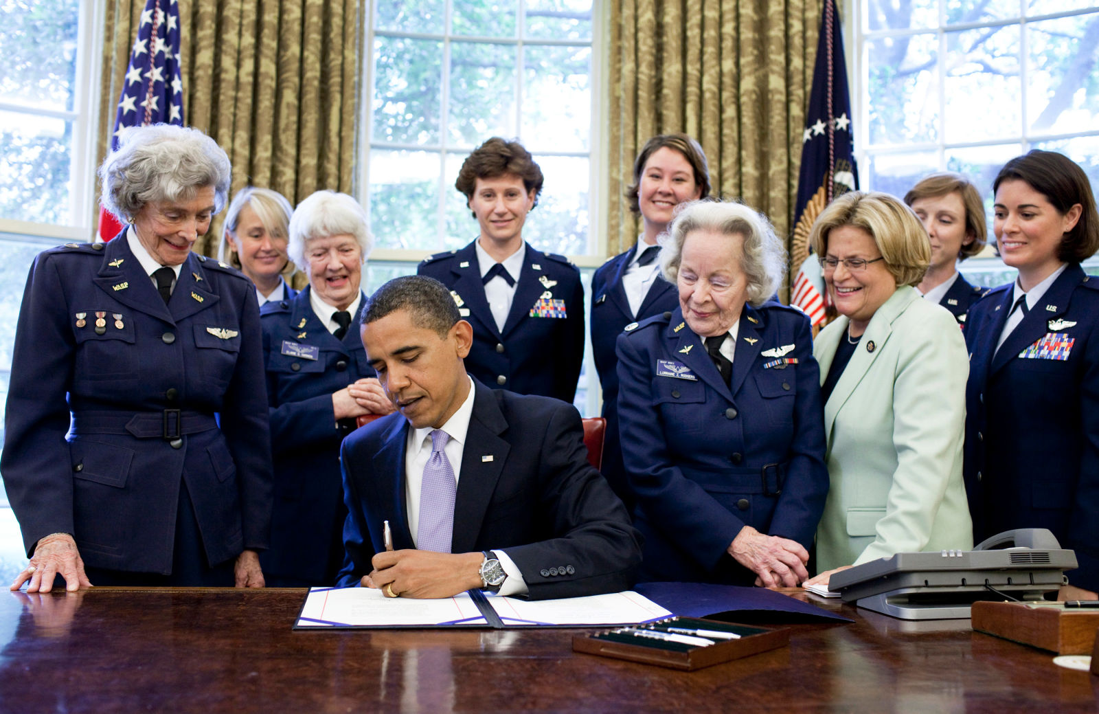 Surrounded by former WASP pilots and current and retired USAF pilots, President Barack Obama signs S.614 in the Oval Office July 1, 2009 at the White House. The bill awards the Congressional Gold Medal to Women Airforce Service Pilots.