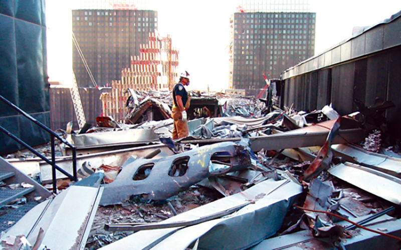 A worker surveys the debris from the collapse of the World Trade Center. A piece of the fuselage from United Flight 175 lies in the foreground. 